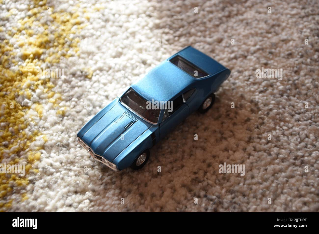 Nahaufnahme eines blauen Spielzeugautos auf einem Teppich Stockfoto