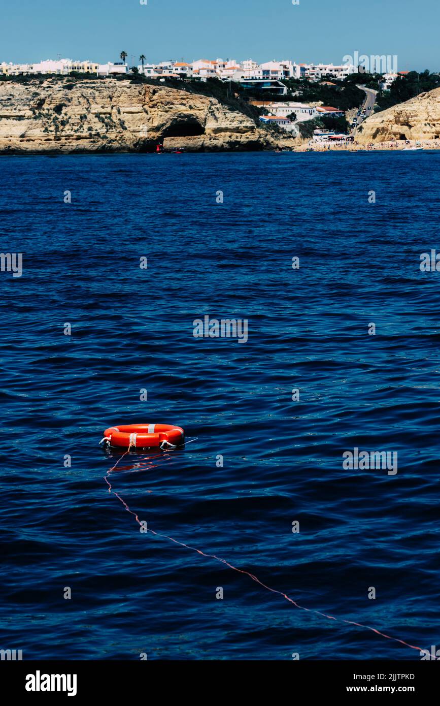 Eine vertikale Aufnahme einer roten Rettungsboje an einer Bucht der Algarve, Portugal Stockfoto