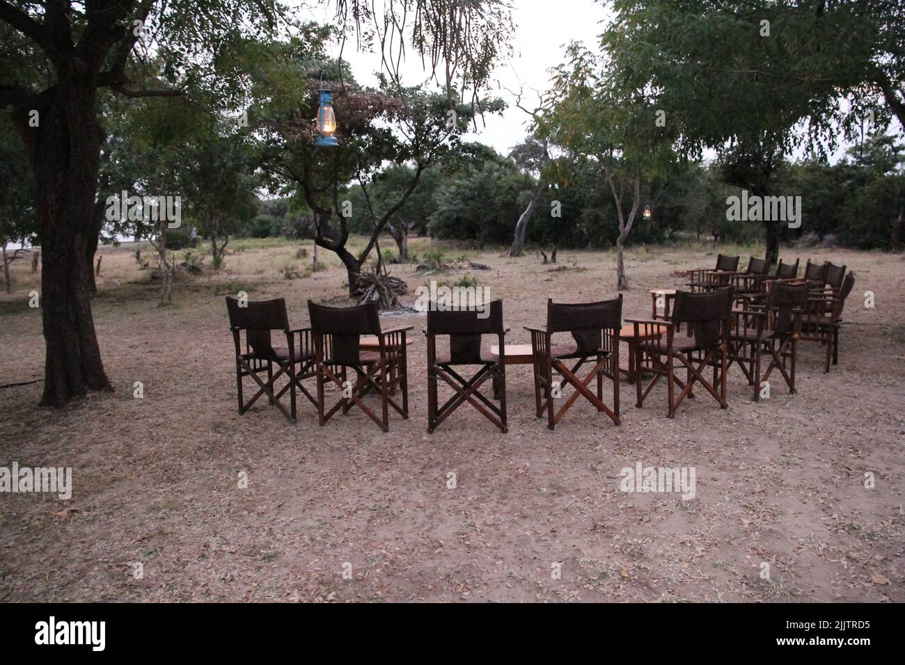 Ein Stuhl um einen Lagerfeuerplatz und Bäume im Selouse Wildreservat in Tansania Stockfoto