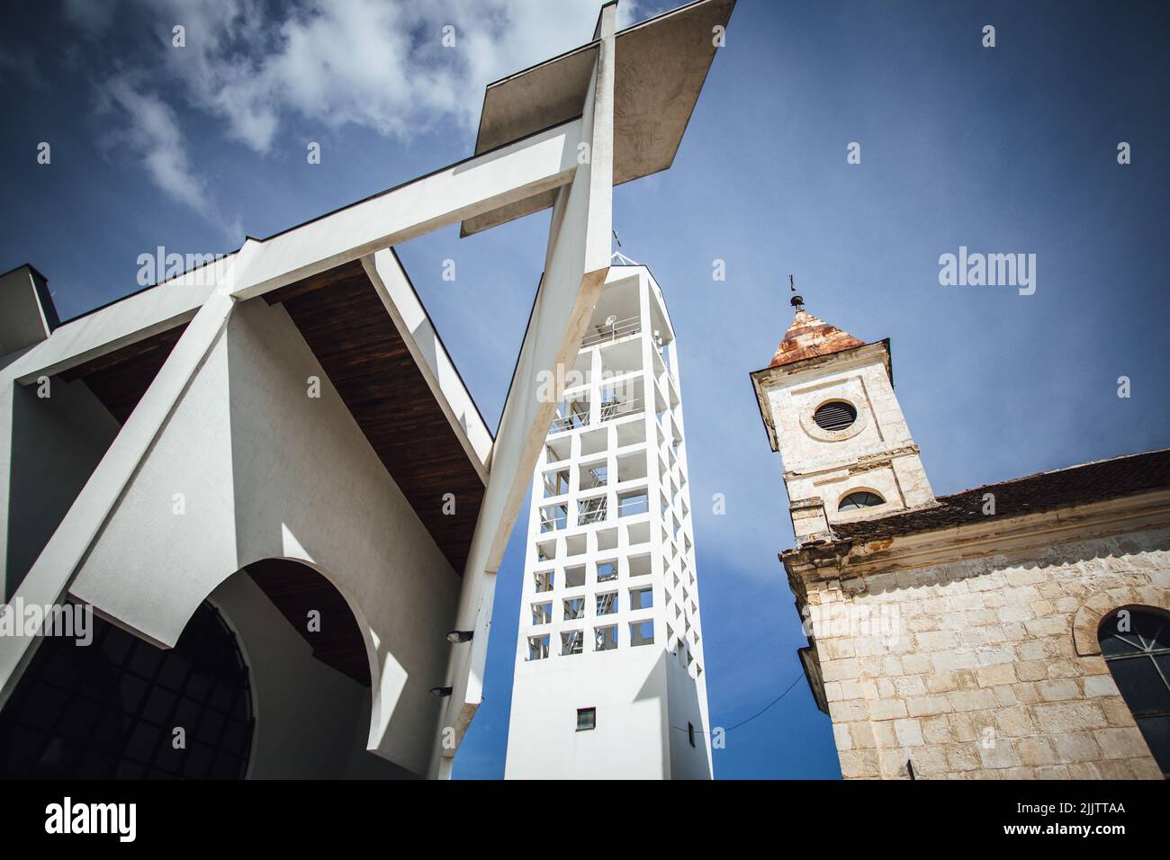 Eine Aufnahme eines Kirchturms neben einem hohen weißen Gebäude in einem niedrigen Winkel Stockfoto