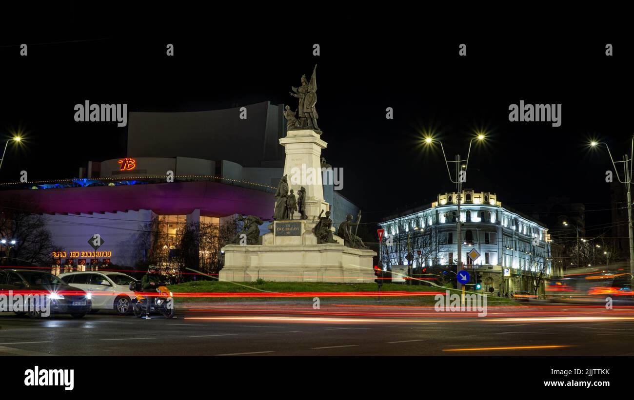 Die Statue von I.C.Bratianu vom Universitätsplatz in der Innenstadt von Bukarest, Rumänien mit Autolampen in Langzeitbelichtung Stockfoto