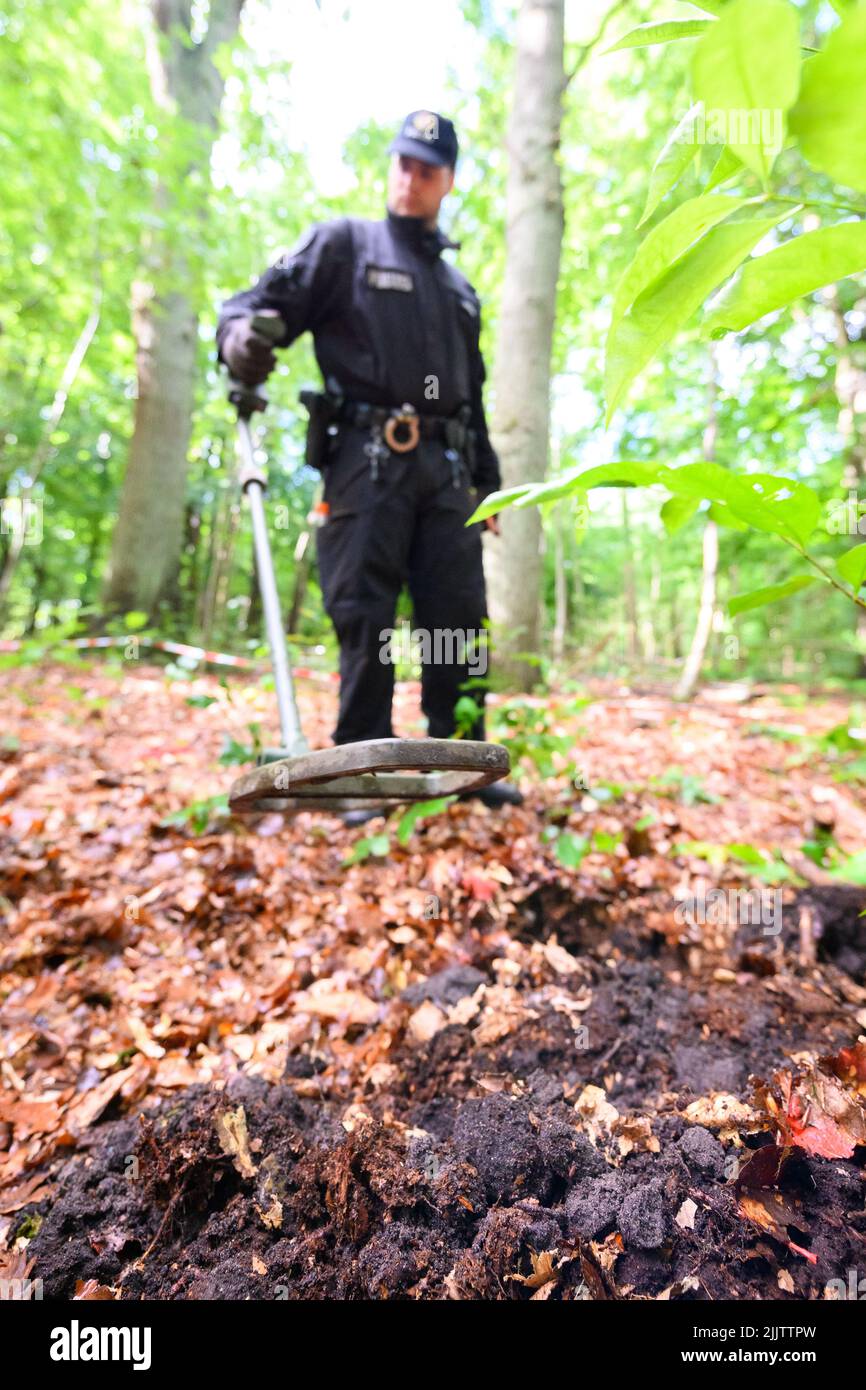 Norderstedt, Deutschland. 13.. Juni 2022. Ein Polizeibeamter untersucht den ausgegrabenen Waldboden mit einem Metalldetektor auf mögliche Spuren. Mehr als zwei Jahrzehnte nach dem Verschwinden der kleinen Hilal hat die Hamburger Polizei einen Waldfleck am nördlichen Stadtrand durchsucht. Quelle: Jonas Walzberg/dpa/Alamy Live News Stockfoto