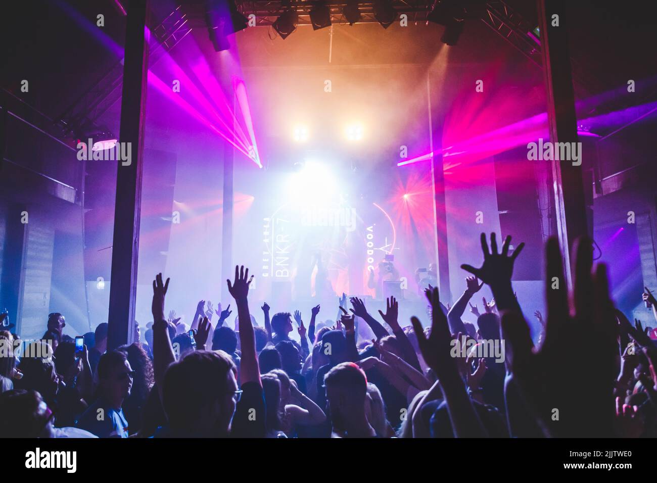 Die Leute jubeln während eines Festivals für elektronische Tanzmusik mit fantastischer Beleuchtung von der Bühne Stockfoto