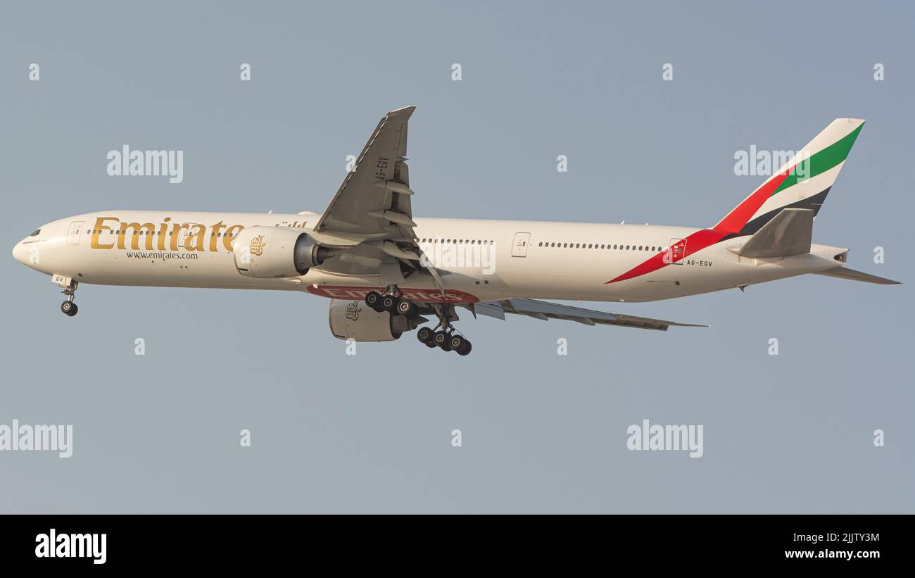Ein Flugzeug der Emirates-Fluggesellschaft Boeing 777-300, das am blauen Himmel vom Dubai International Airport fliegt Stockfoto