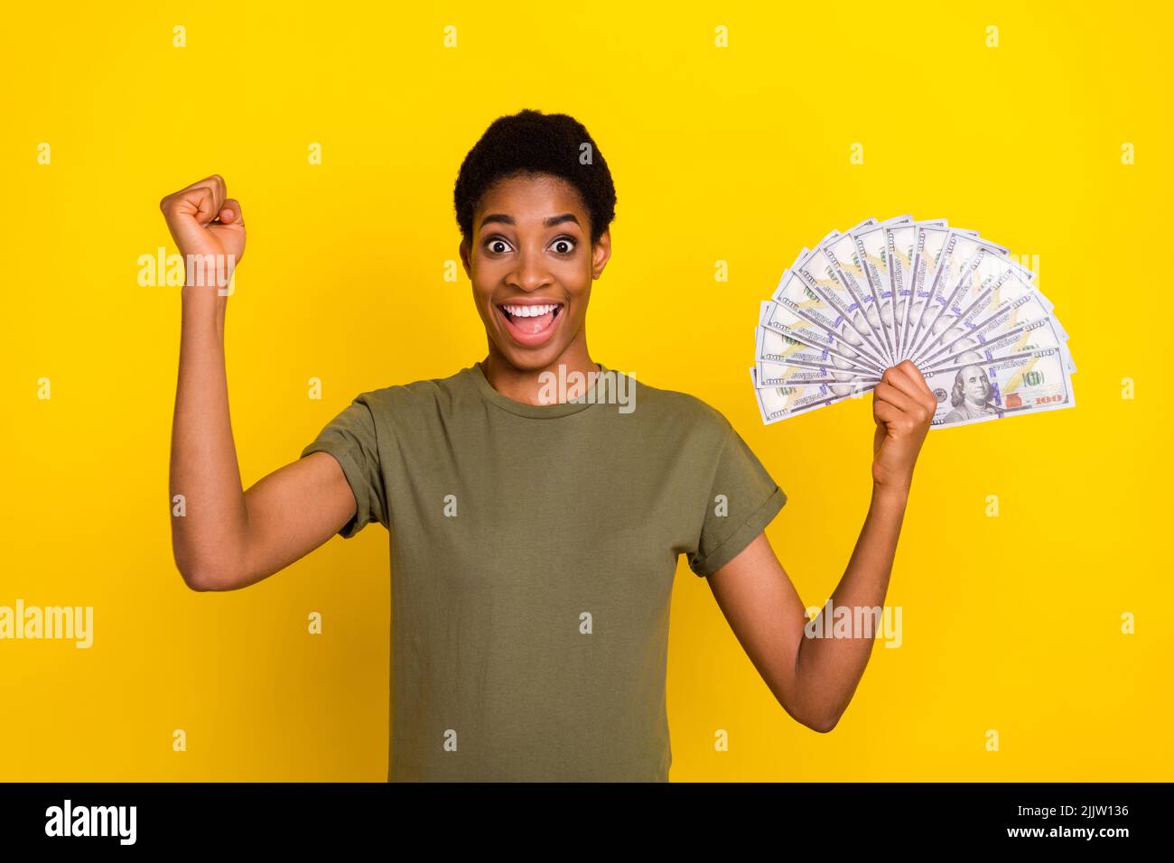 Porträt einer erfolgreichen positiven Person heben Faust halten Cashback-Banknoten auf gelbem Hintergrund isoliert Stockfoto