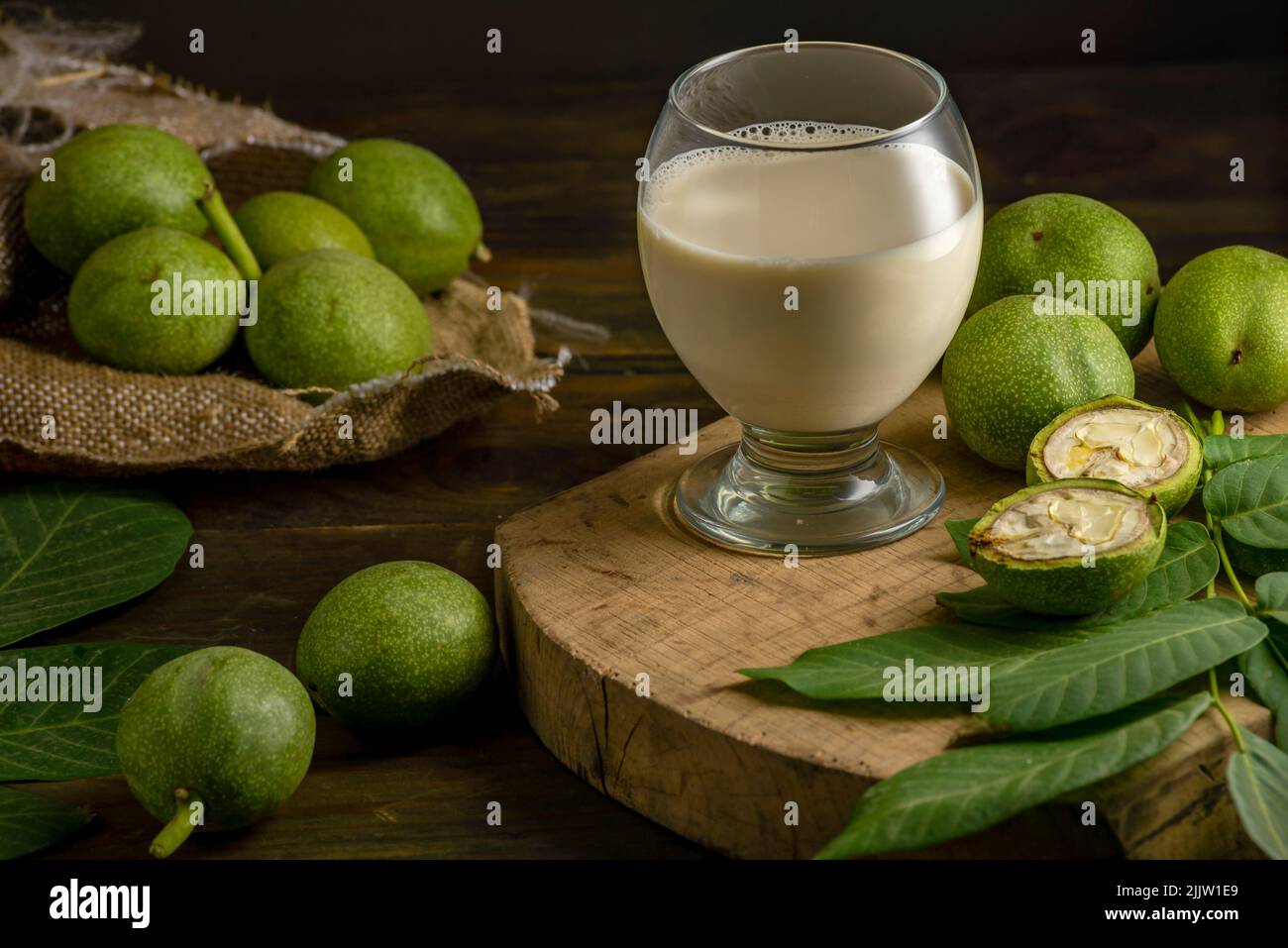 Grüne Walnusskerne Blätter Holztisch Ölnüsse unreife Schalen gesundes Essen Getränk, alter rustikaler Tisch Hintergrund Ernte, Bio hausgemachte Pflanze basiert Stockfoto