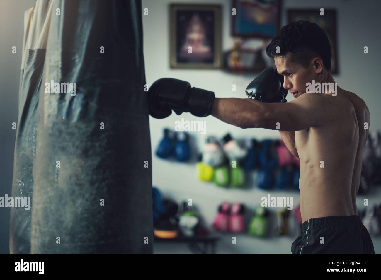 Ein männlicher Boxer trifft im Fitnessstudio mit Boxhandschuhen auf einen  Boxsack Stockfotografie - Alamy