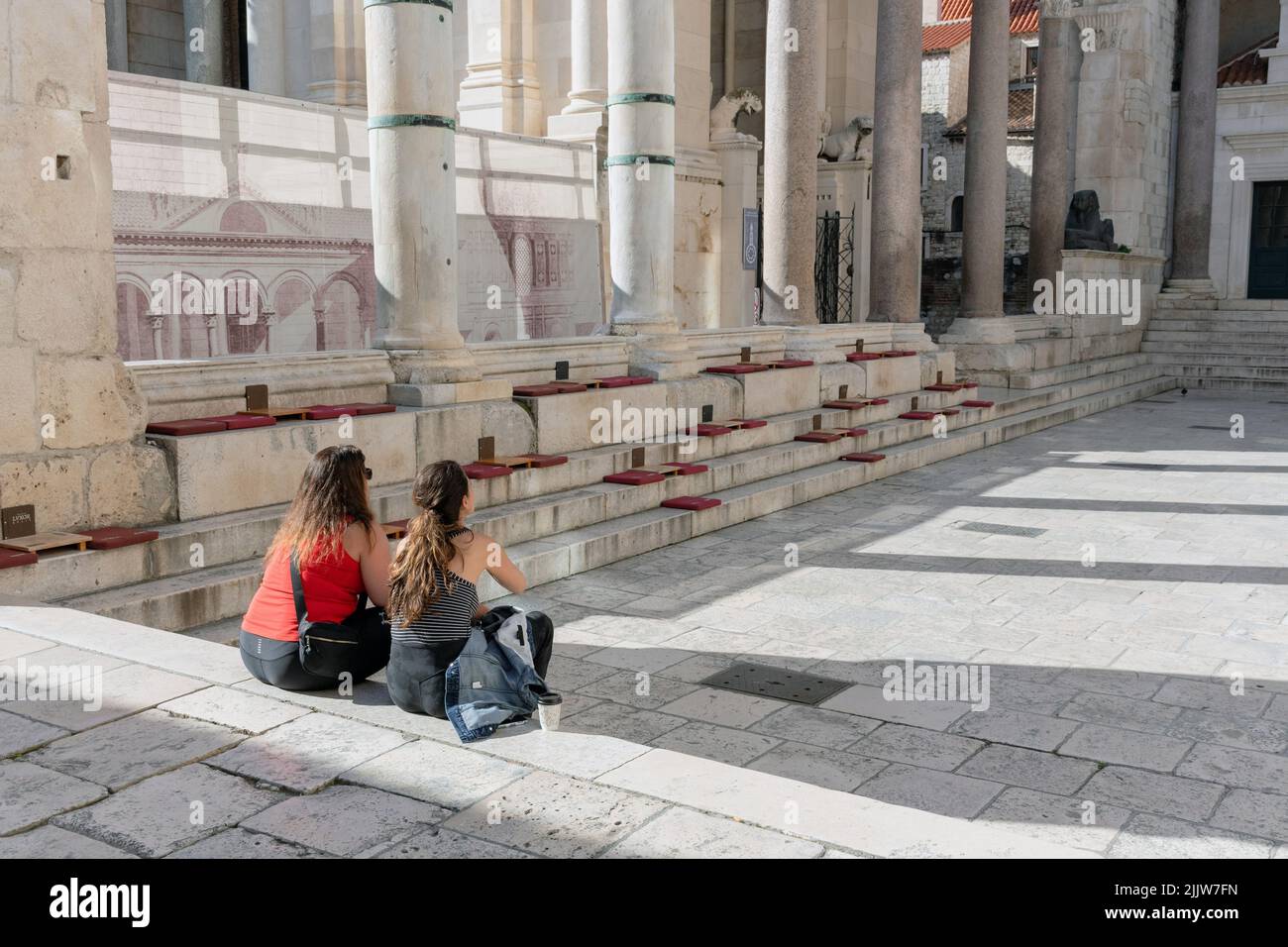 Nahaufnahme von zwei Frauen, die auf einer Treppe auf dem Peristyle im Diokletianpalast in Split, Kroatien, sitzen Stockfoto