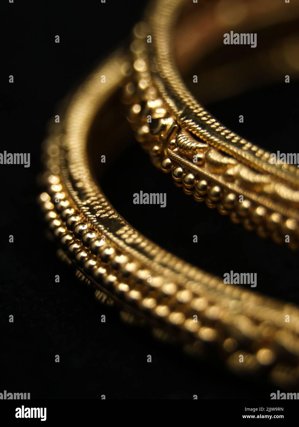 Goldene Vintage-Armreifen mit verzierten Details, die in einem Nahaufnahme-Makro-Foto auf schwarzem Hintergrund eingefangen wurden Stockfoto