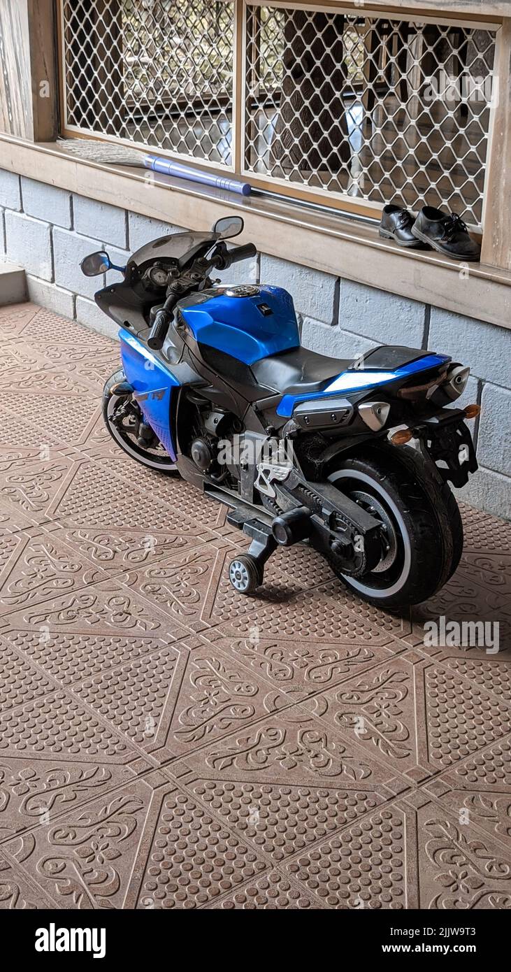 Ein blaues Motorrad für Kinder mit Trainingsrädern, die auf der Straße geparkt sind Stockfoto