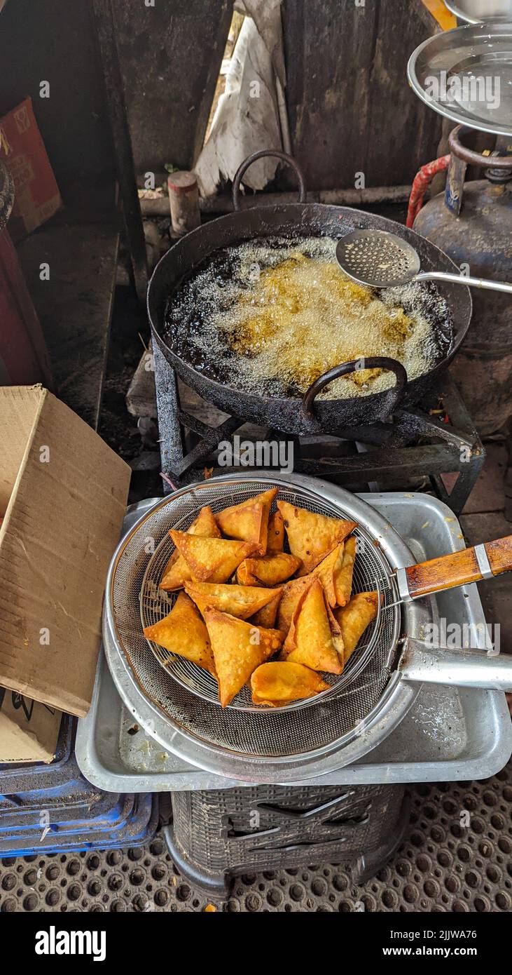 Knusprige und würzige Samosa-Snacks goldbraun in der Farbe, frisch in heißem, kochendem Öl im Lebensmittelgeschäft zubereitet Stockfoto