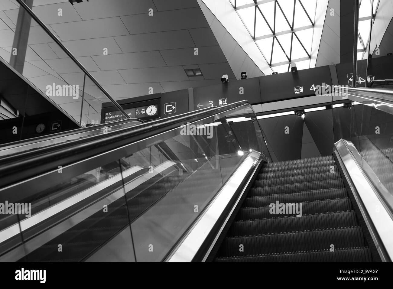 Eine Graustufenaufnahme einer Rolltreppe zum Bahnsteig am Hauptbahnhof in Wien, Österreich Stockfoto