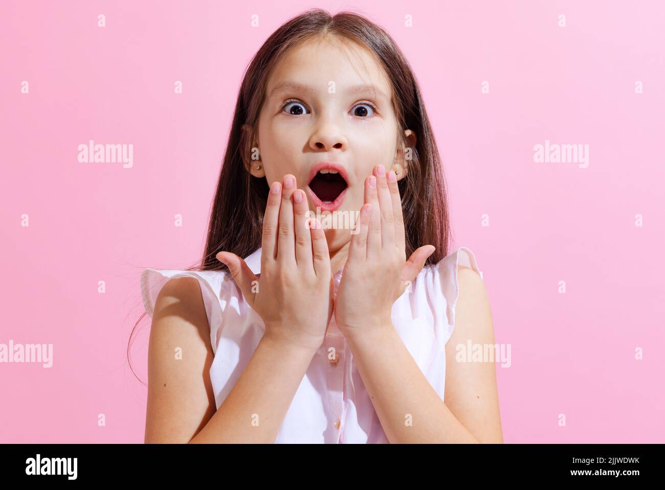 Überrascht kleine charmante Mädchen, Kind Blick auf die Kamera mit offenem Mund isoliert auf rosa Hintergrund. Konzept der Kinder Emotionen, Mode, Schönheit Stockfoto
