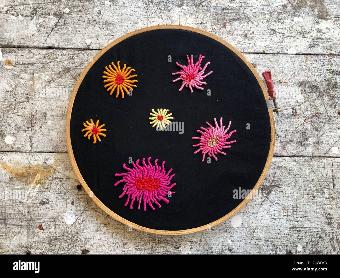 Boolesche Stitch-Blume mit französischer Knoten-Stickerei auf schwarzem Stoff Stockfoto