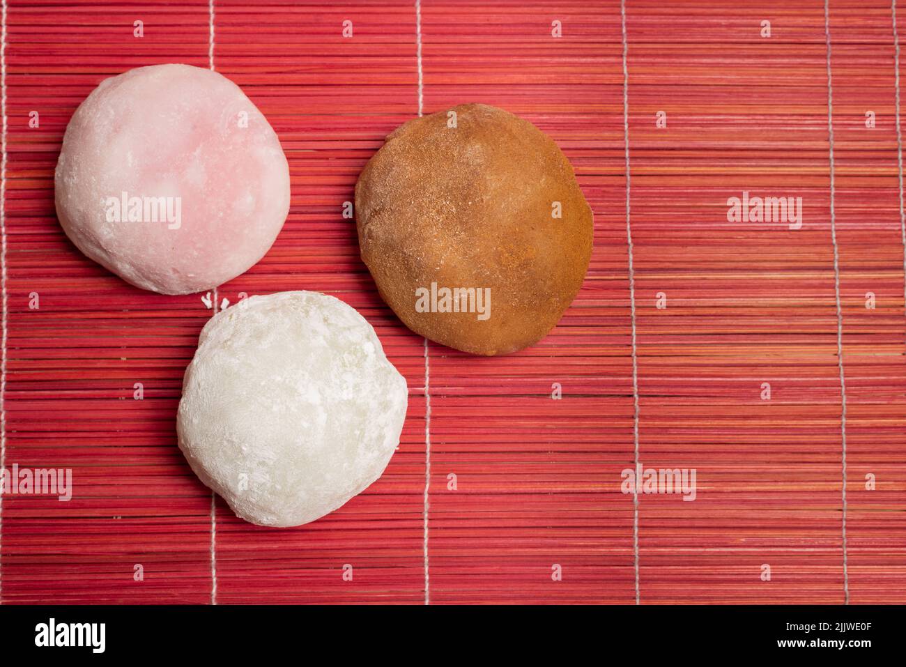 Handwerklich hergestellter mochis in drei Geschmacksrichtungen auf roter Holztischdecke mit Kopierfläche Stockfoto