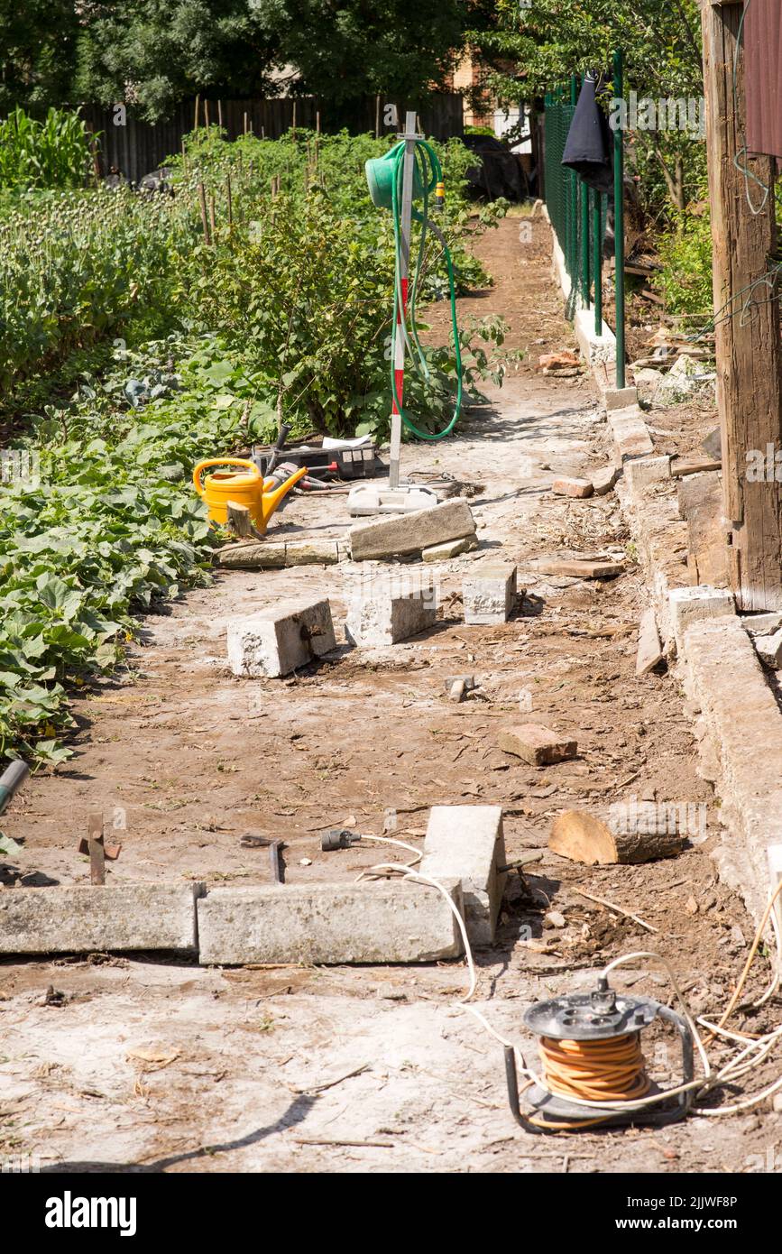Ersetzt den alten Gartenzaun durch einen neuen. Bau neuer Maschendrahtzaun im Garten des Hauses Stockfoto
