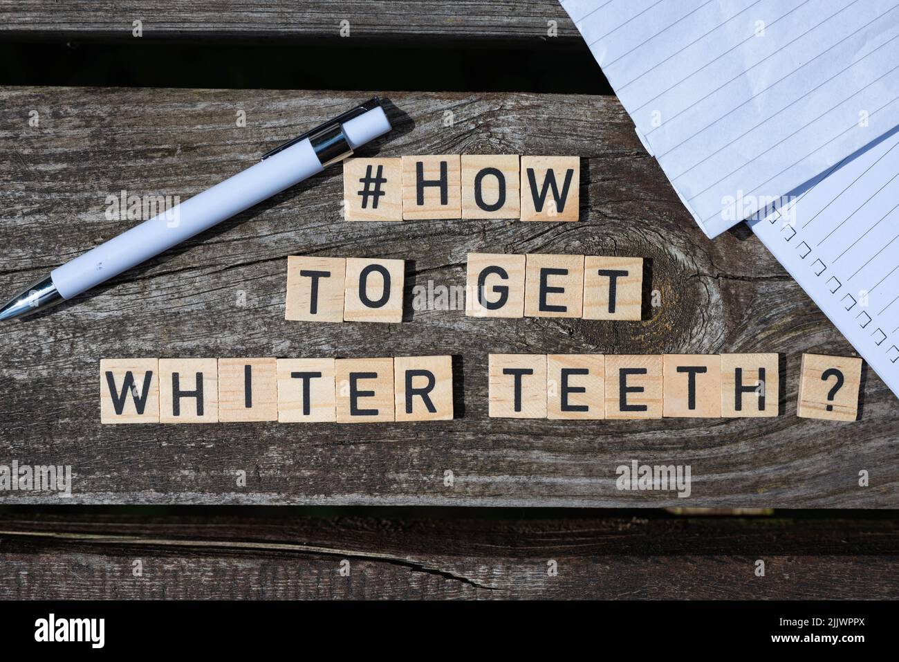 Wie man weißere Zähne bekommt Frage Buchstaben auf Holzblöcken auf einem Holztisch mit Bleistift und Papier an den Seiten des Schusses Stockfoto