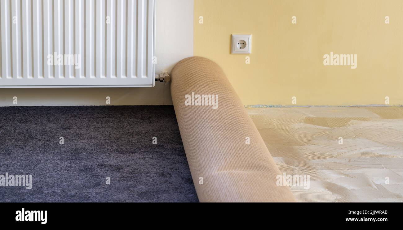Einbau eines neuen Teppichs durch Aufkleben des Teppichs auf den Boden. Stockfoto