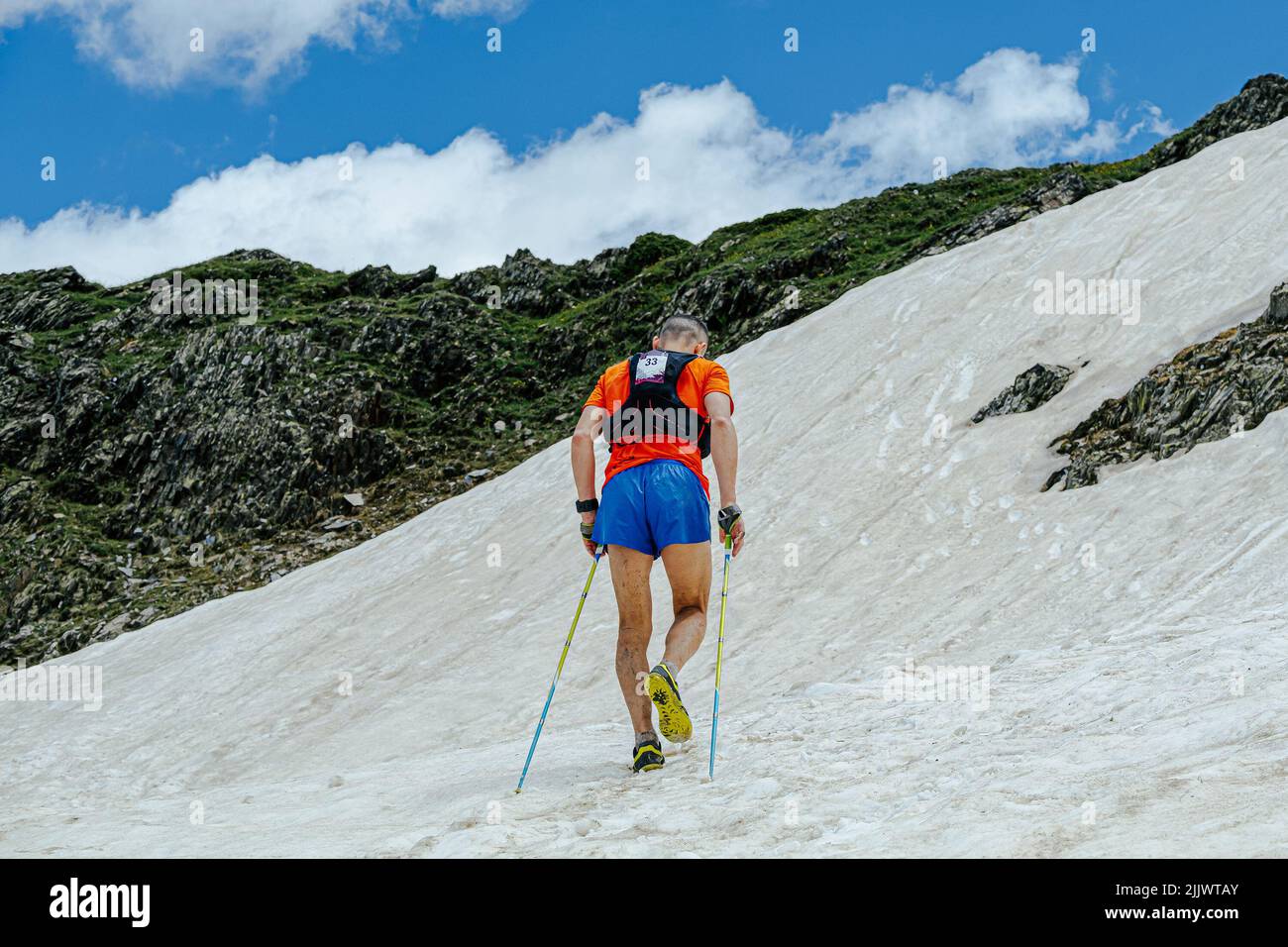 Männlicher Athlet, der während eines Ultra-Marathons verschneit bergauf klettert Stockfoto