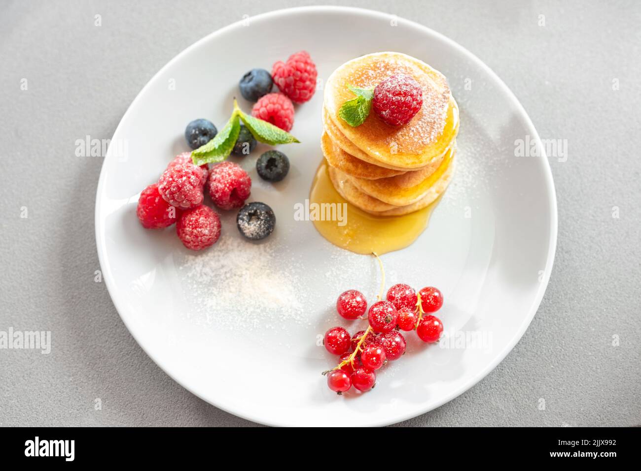 Pfannkuchen mit Puderzucker und Honig auf hellem Hintergrund. Essen für Vegetarier gesunde Ernährung. Frühstück für die ganze Familie. Stockfoto