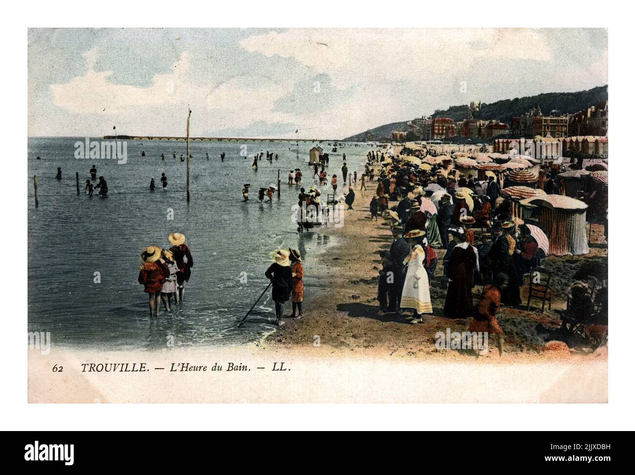 Menschen am Strand des Luxus-Badeortes TROUVILLE, FRANKREICH, um 1904. Vintage-Postkarte gedruckt in Frankreich isoliert auf schwarzem Hintergrund. Stockfoto