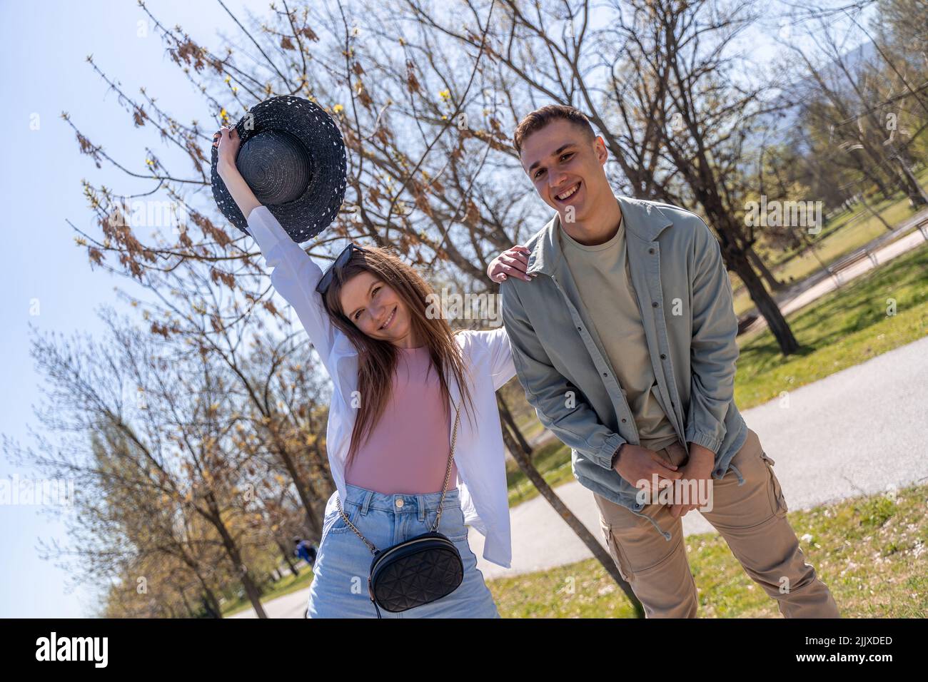 Fröhliche attraktive Mann und Frau mit viel Spaß im Freien, erzählen Witze, genießen warmen Tag. Foto in voller Länge Stockfoto