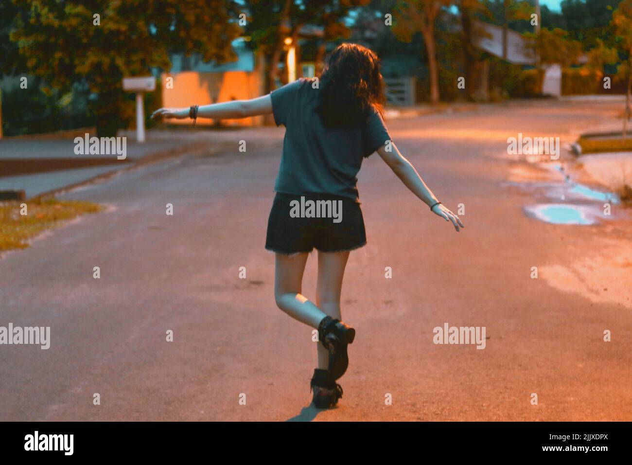 Junge Frau, die allein in der dunklen Straße tanzt Stockfoto