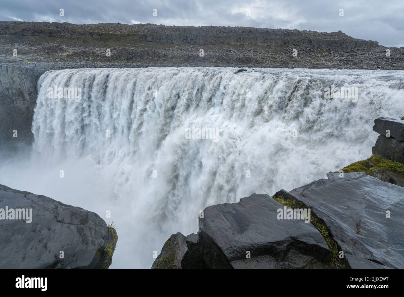 Größter Wasserfall Europas, Dettifoss. Schlammiges Wasser fällt über den Rand. Majestätischer isländischer Wasserfall an einem regnerischen, bewölkten Tag. Stockfoto
