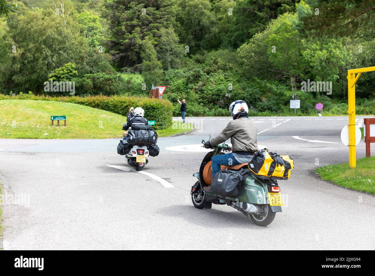 Scooter-Fahrer, mit Campingausrüstung auf dem Roller, Touren Schottland auf zwei Rädern, verlassen Glen Coe, Highlands, Schottland, Großbritannien Stockfoto