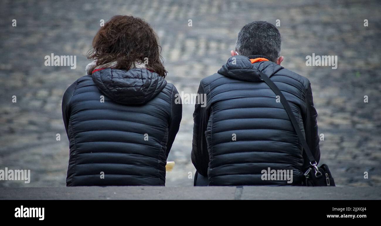 Eine Nahaufnahme der Rückseite eines Paares in gepolsterten Jacken sitzen und freuen sich nach vorne Stockfoto
