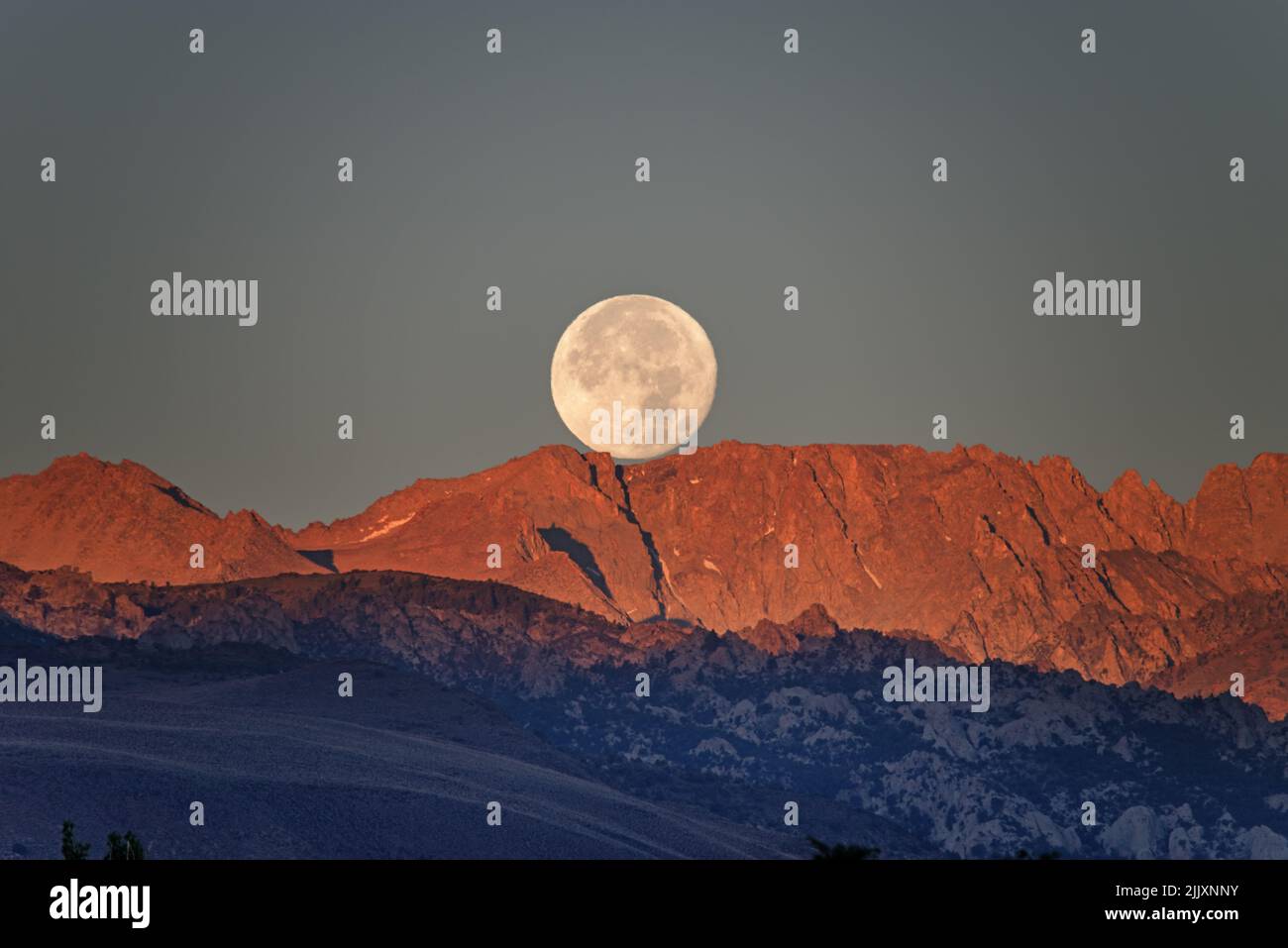 Der Vollmond untergeht bei Sonnenaufgang über dem Mount Lamarck in den Sierra Nevada Mountains, von Bishop California aus gesehen Stockfoto