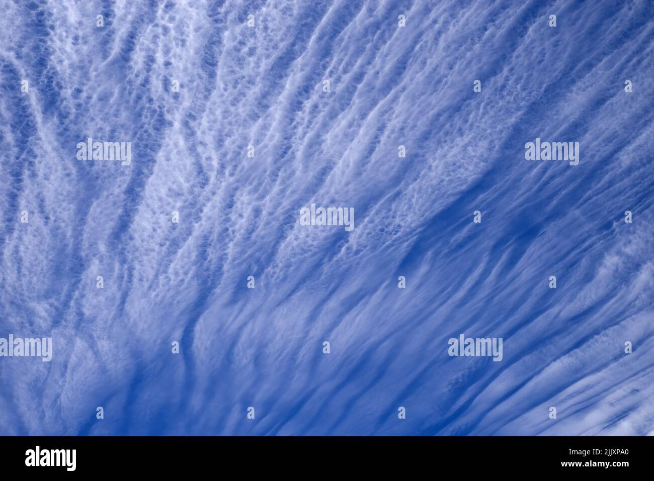 Wispy weiße Streifen Cirrus Wolken mit einem blauen Himmel hinter ihnen Stockfoto