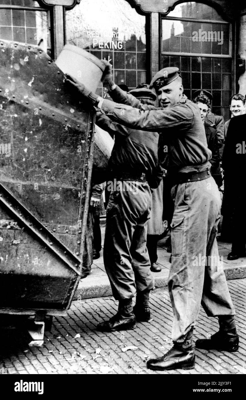 Amsterdamer Staubmänner ziehen in den Streik: Truppen übernehmen Aufgaben - niederländische Soldaten arbeiten mit Staubkarren in den Straßen von Amsterdam. Aufgrund eines Streiks von Müllmännern in Amsterdam wurden Truppen gerufen, um bei der Beseitigung des angesammelten Mülls und Mülls zu helfen. 05. April 1955. (Foto von Sport & General Press Agency Limited.) Stockfoto