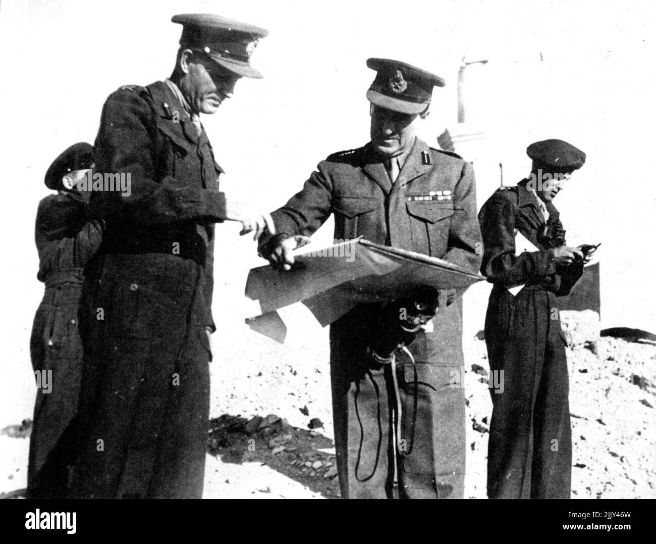 General Paget Tours Cyrenaica - General Paget verweist auf eine Karte der Schlachtfelder von Sidi Abdel Rahaman. Mit ihm sind Generalmajor J. W. Reeve, stellvertretender Adjutant-General, und Major Phillmore (rechts). General Sir Bernard O. T. Page. Der Oberbefehlshaber, Naher Osten, besuchte vor kurzem während einer Tour durch die westliche Wüste und Cyrenaica viele der alten Schlachtfelder der Wüste. Er reiste nach Tobruck in einem Sonderzug der ägyptischen Staatsbahnen. 01. Januar 1945. (Foto von Planet News Ltd.) Stockfoto