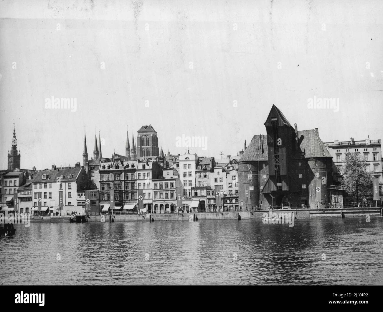Er 15. Jahrhundert Krantor, bekannt für seine Stein-und Holzkonstruktion und jetzt mit dem Nazi-Hakenkreuz geschmückt. Ganz links sieht man den anmutigen Turm des Rathauses und in der Mitte den soliden Turm der Marienkirche, einer der bekanntesten Kirchen der Stadt. Von Ostpreußen sollen eintausendvierhundert bewaffnete Deutsche und LKW-Ladungen von Waffen und Munitionsmaterial aus Danzig eingetroffen sein. Gerüchte über einen bevorstehenden Putsch kursieren. Mehr als 2.000 Angehörige der deutschen Streitkräfte sollen sich nun in Danzig befinden, und es werden auch polnische Militärvorbereitungen gemeldet. 28. Juni 1939. Stockfoto