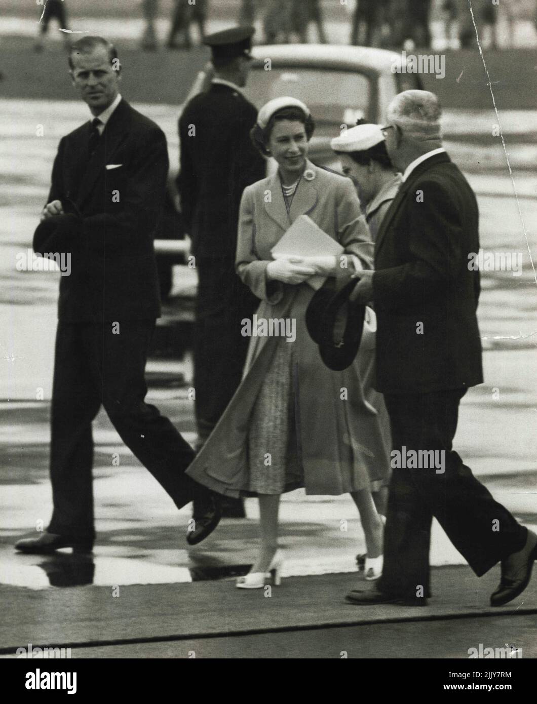 Abflug - die Königin plaudert mit dem stellvertretenden Premierminister Heffron, als sie über den Asphalt in Mascot zum Royal-Flugzeug für ihren Flug nach Bathurst geht. Frau Hefforn ist teilweise verdeckt. 12. Februar 1954. Stockfoto