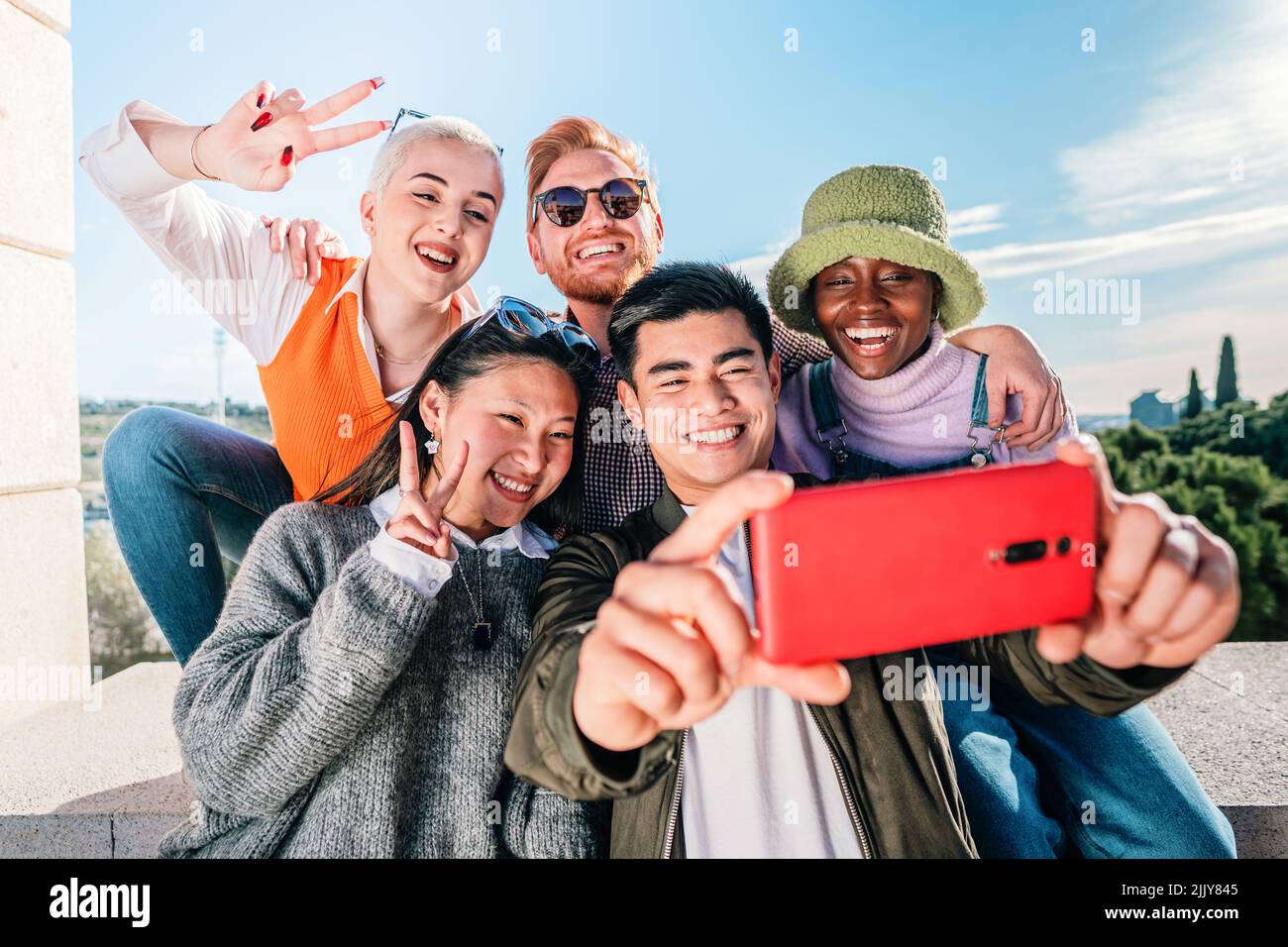Fünf multirassische Freunde, die ein Foto mit einem Handy machen, das vor der Kamera posiert und lächelt. Stockfoto