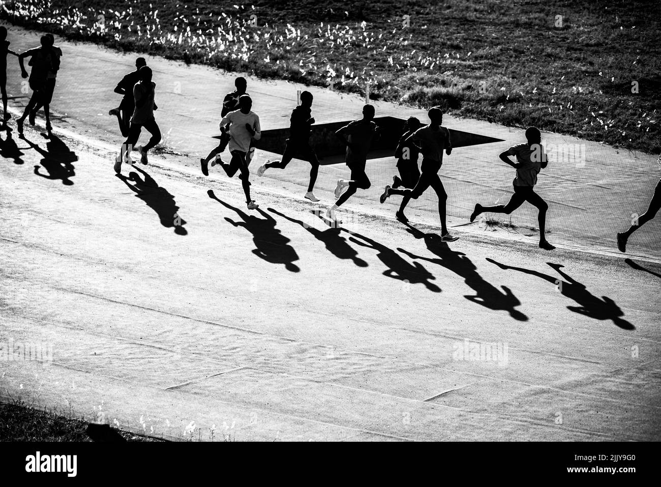 Gruppenausbildung in Kenia. Eine große Gruppe kenianischer Läufer bereitet sich auf das Rennen vor. Ausdauerläufer und Marathonprofis laufen auf dem roten Boden o Stockfoto