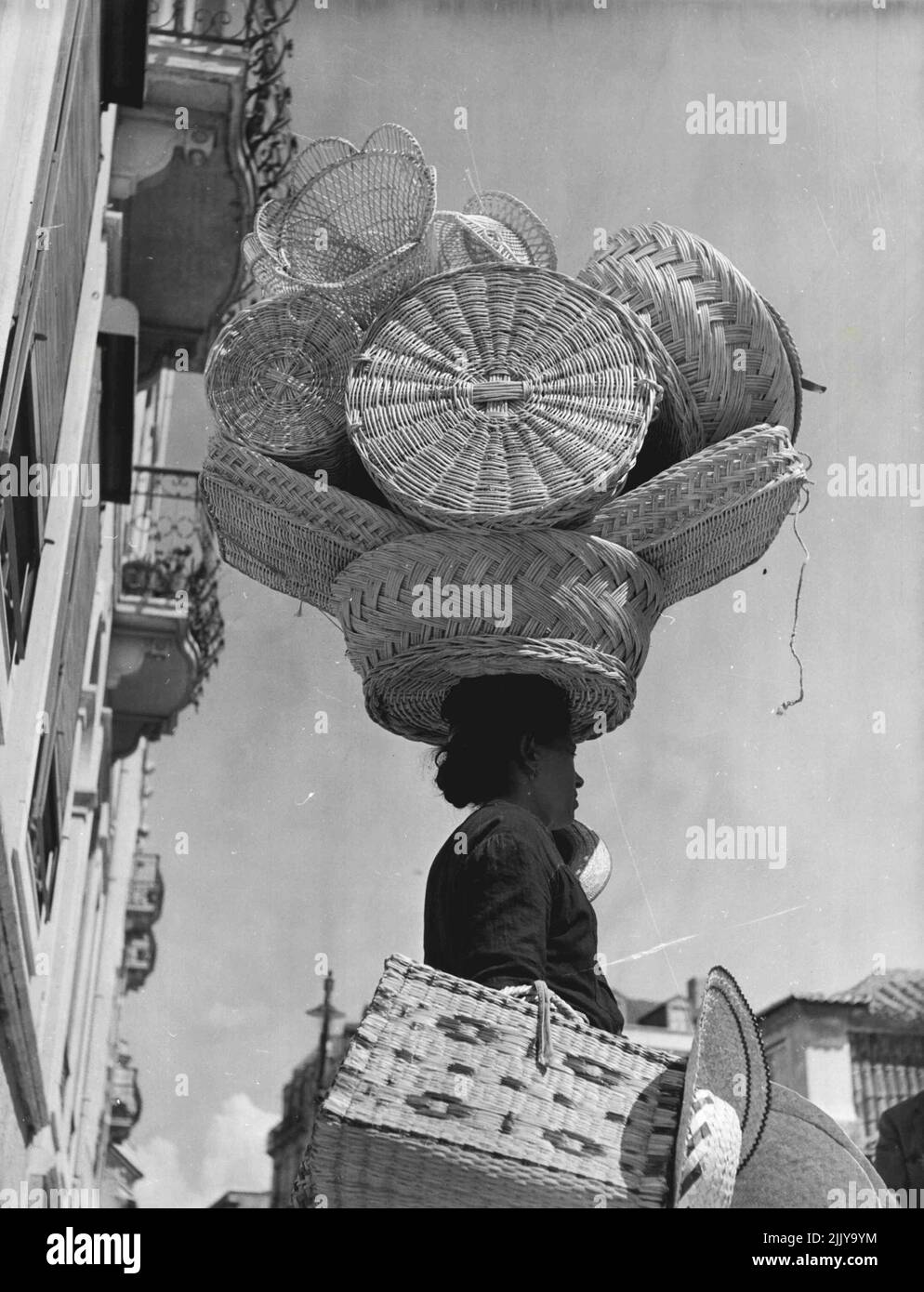 Arbeiterinnen Portugals -- Manchmal sind die Straßenverkäuferinnen ein buntes Bild wie bei diesem Korbskarr, der mit zarten Frauen beladen, aber stark gemachten Körben und Hass durch die Straßen geht. 30. September 1949. (Foto von Steven Henty, Pictorial Press). Stockfoto