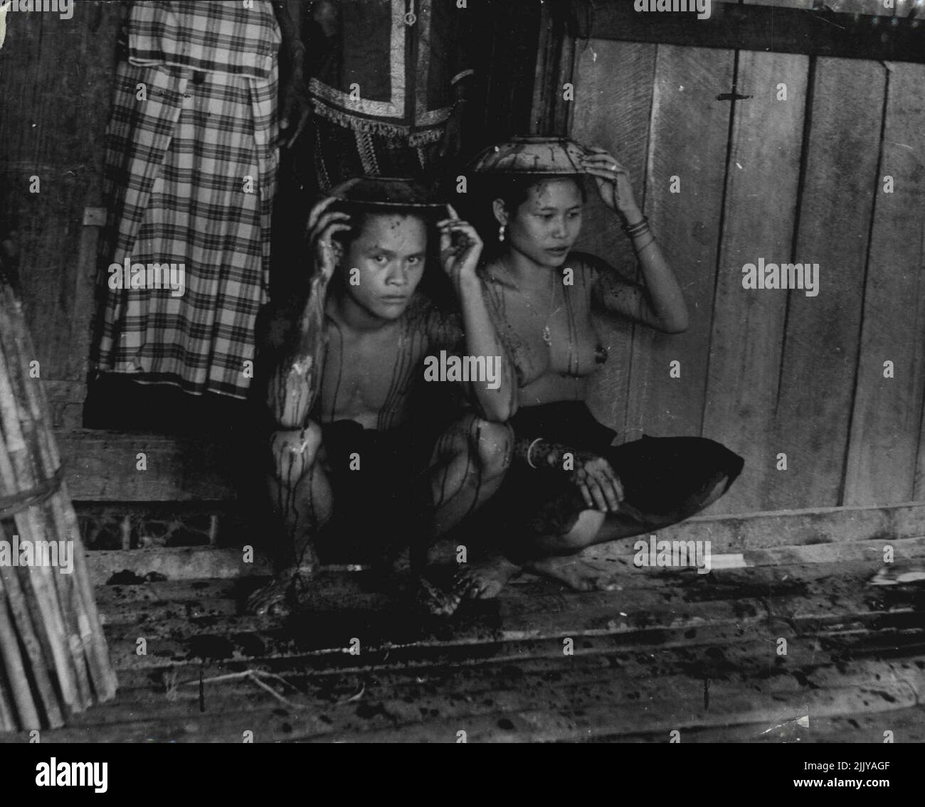 Land Dayaks of Borneo Purification: Ein frisch verheiratetes Paar wird von schädlichen Einflüssen durch das Blut eines Schweins gereinigt, das über ihren Köpfen geschlachtet wurde. Dies ist Teil einer melodramatischen Geistzeremonie, die sich vom Ahnenkult unterscheidet. Ein frisch verheiratetes Paar wird durch das Blut eines Schweins gereinigt, das über ihren Köpfen getötet wurde. 8. März 1952. (Foto von W.R. Geddes, Camera Press). Stockfoto