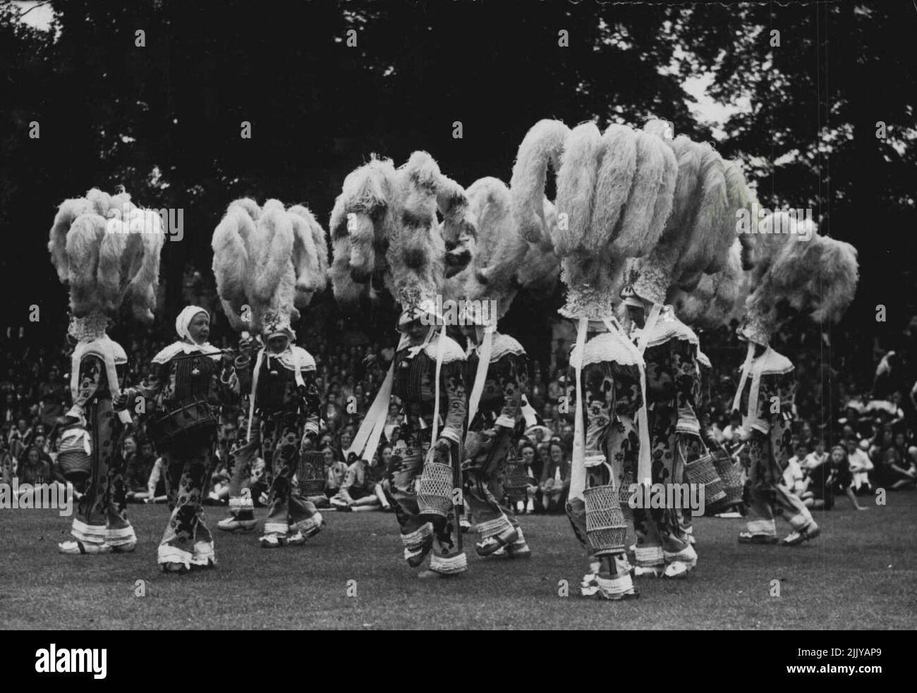 London bewundert die Federn - auffällige Kopfkleider, wie sie die belgischen Darsteller während des Internationalen Folk Dancing Festivals im Cockpit, Hyde Park, London, tragen. Die gefiederten Kopfkleider stammen aus dem 14.. Jahrhundert und waren in den Vorkriegsjahren ein berühmtes Merkmal des Binche-Karnevals (Belgien). Die Ausstellung findet unter der Schirmherrschaft der Girl Guides Association statt, und Teams von Guides und Pfadfindern aus vielen Teilen der Welt sind dabei. 14. Juli 1947. (Foto: Sport & General Press Agency, Limited). Stockfoto