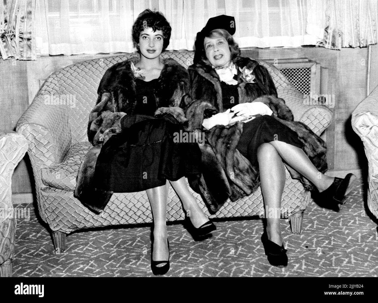 Ich bin nach London, um ihr Buch der Memoiren zu starten. Die berühmte Mistinguett, die Königin der Pariser Musikhalle, die sich geweigert hat, abzudanken, der Liebling der Folies Bergere, die vier Könige unter ihren Bewunderern zählte, ist um die 80, dachte, sie sehe es nicht aus. Sie trägt einen schweren Nerzmantel, der auf dem Revers eine große Orchidee trägt, die einen schwarzen Hut hat. Als Mistinguett den Saum ihres Rockes hochhob und ihre schwarzen Seidenstrümpfe mit leicht geschlagenem Laderaum enthüllte, war ihre Nichte Mlle. Micky zog ihren eigenen Rock weiter nach unten. Mlle. Micky ist Schauspielerin - aber nicht in der Musik --Halle. 10. Oktober 1954. (Foto von Sunday Express Picture). Stockfoto