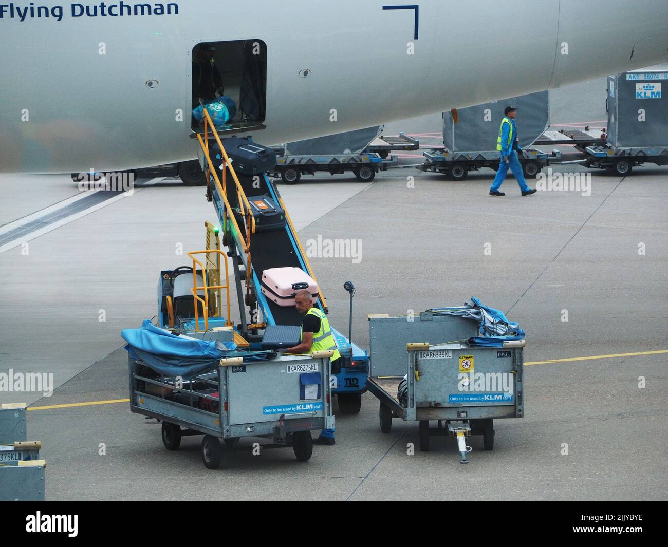 Gepäckabfertiger, die ein KLM-Flugzeug am Flughafen Schiphol, Amsterdam, Niederlande entladen Stockfoto
