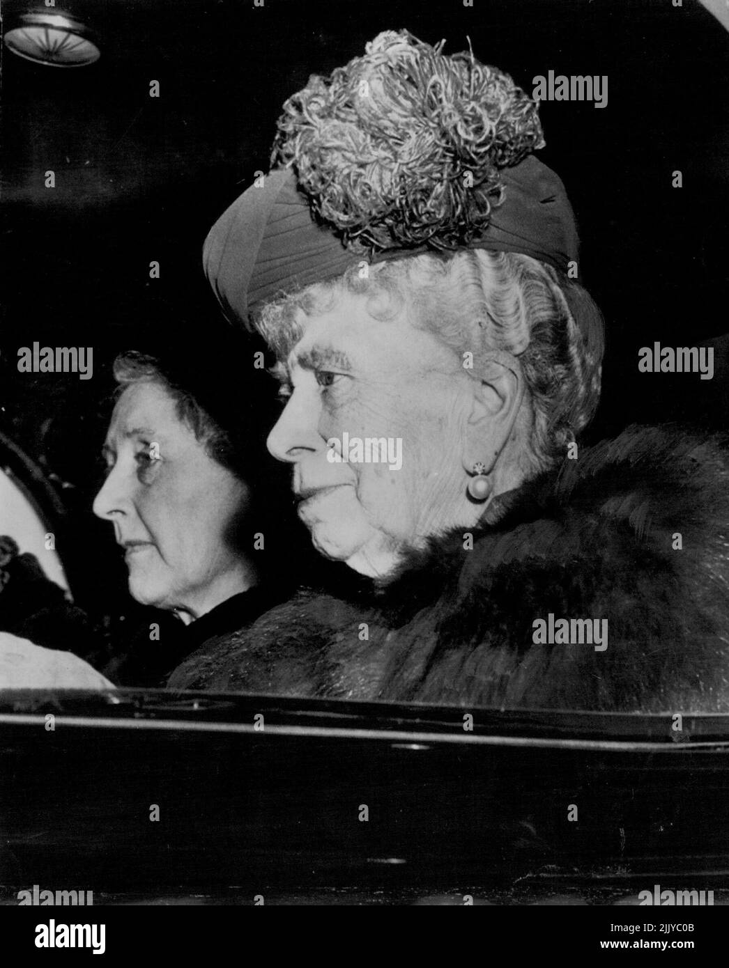 Eine königliche Dame kehrt nach London zurück -- die Dowager Queen Mary hat eine ihrer markanten Hauben, als sie gestern nach einem längeren Weihnachtsaufenthalt in Sandringham, dem Royal Castle in Norfolk, in ihre Londoner Residenz zurückkehrt. Eine nicht identifizierte Dame, die wartet, begleitet die alternde Königin. 30. Januar 1953. (Foto von AP Wirephoto). Stockfoto