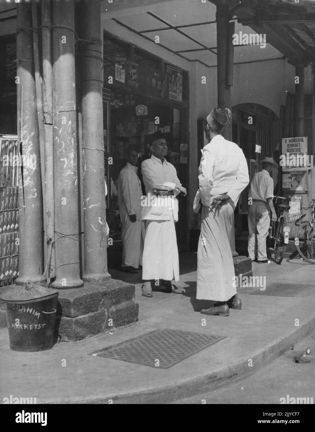 In Malaya ist immer Zeit für einen Klatsch. Straßenecke Klatsch sind indische Händler. Aufgenommen in Singapur. 21. Dezember 1955. (Foto von Ross/Fairfax Media). Stockfoto