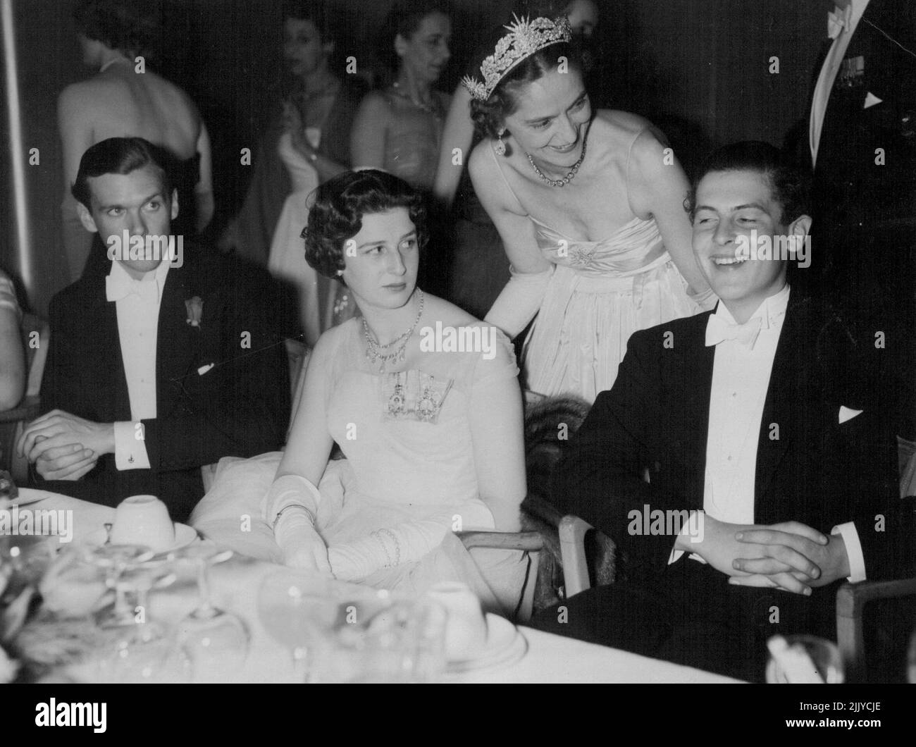 Lively Party - Einen Witz teilen beim Rose Ball im Grosvenor House, London, gestern Abend sind Mr. James Ogilvy und Lady Howard de Waldon. (Stehend) Prinzessin Alexandra in einem ***** Kleid aus weißem Tüll sitzt links. 5.Mai 1955. (Foto von Evening Standard Picture). Stockfoto