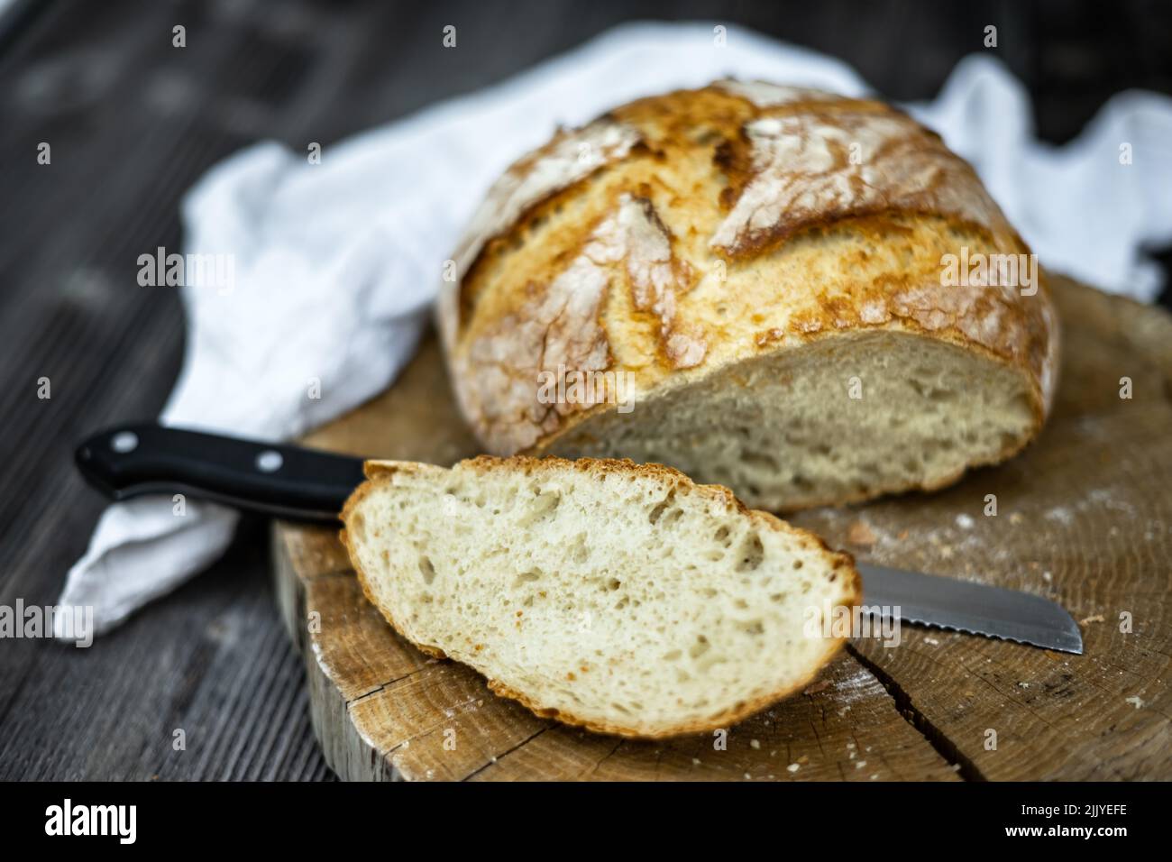 Traditionelles Sauerteig-Brot, das auf einem rustikalen Holztisch in Scheiben geschnitten wird. Fotos von gesunden Lebensmitteln Stockfoto