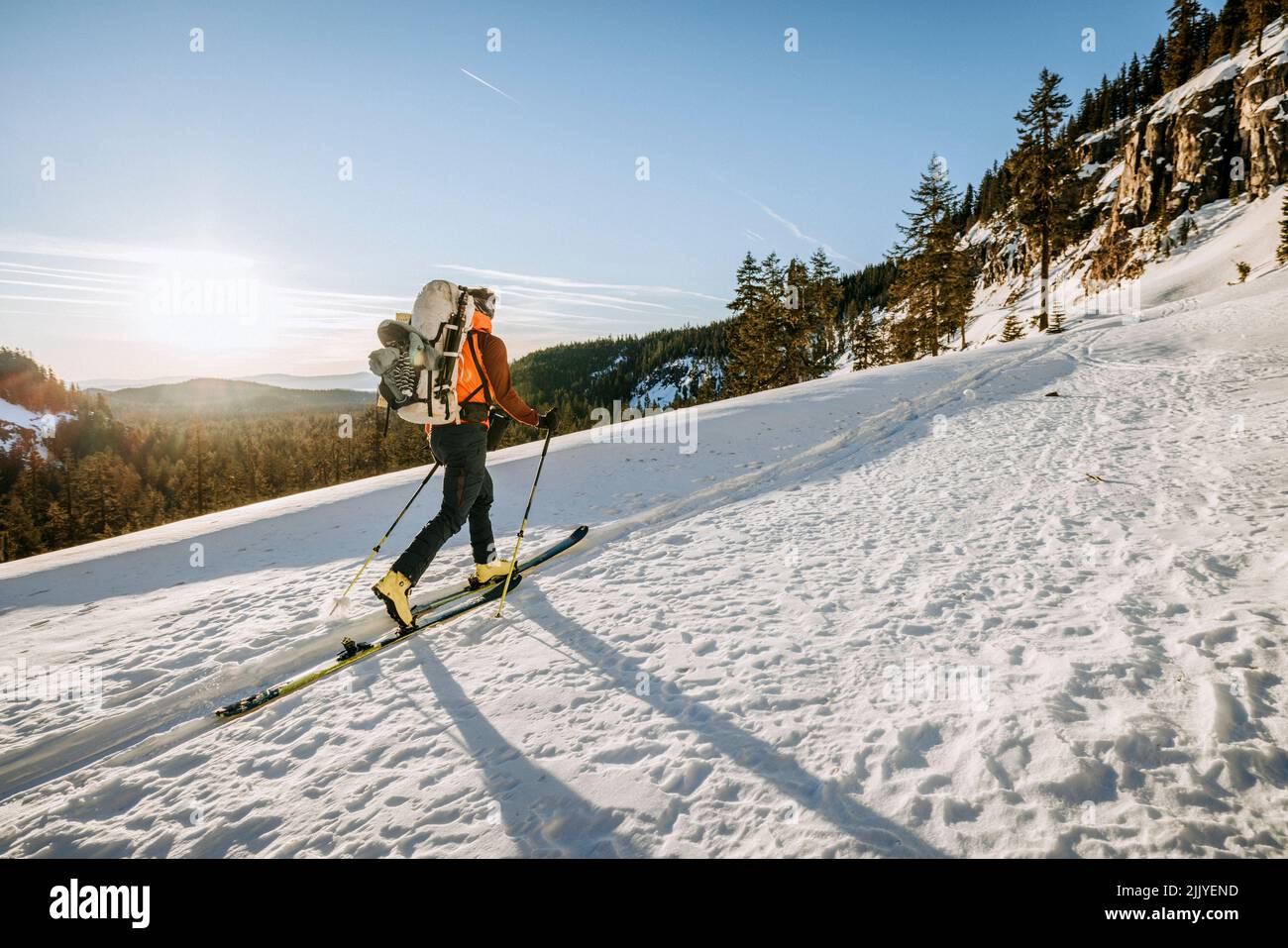 Man fährt bei Sonnenaufgang in der Nähe des Crater Lake, Oregon, Ski entlang einer winterlich verschneiten Piste Stockfoto