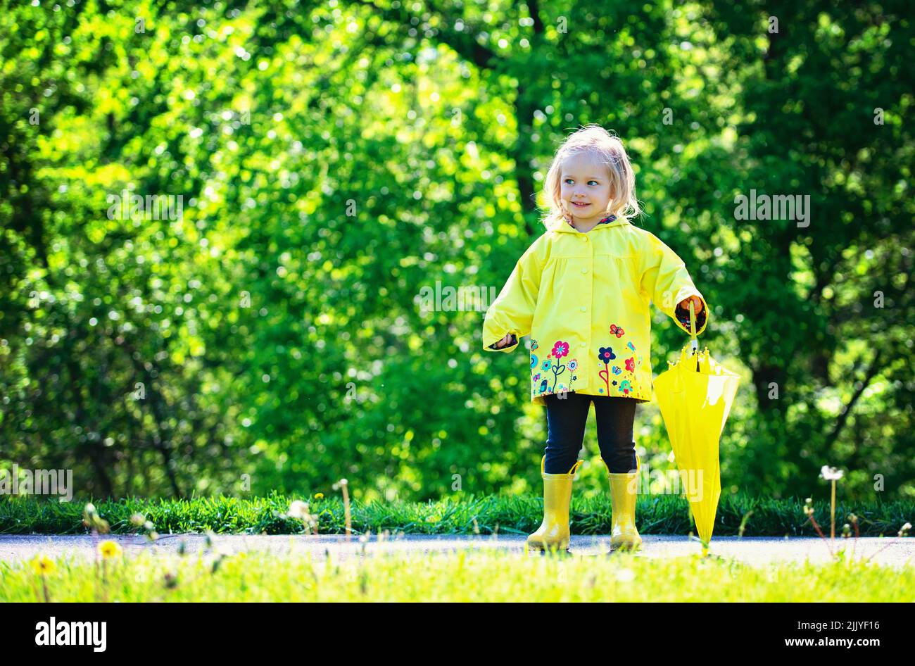 Blonde Kleinkind Mädchen in gelben Regenmantel. Stockfoto