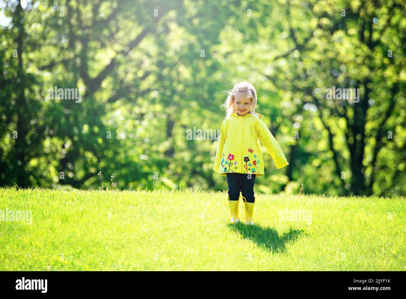 Blonde Kleinkind Mädchen in gelben Regenmantel. Stockfoto